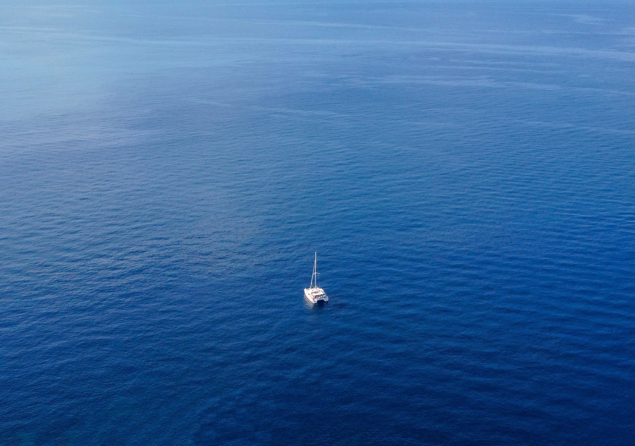 Calm blue sea with singe catamaran sailing