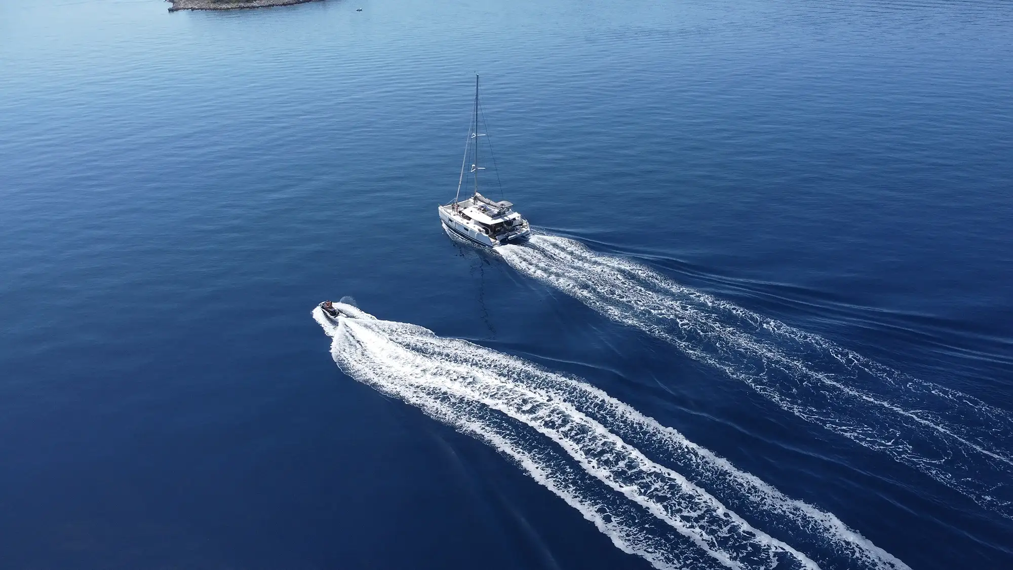 A catamaran and a speed boat sail together